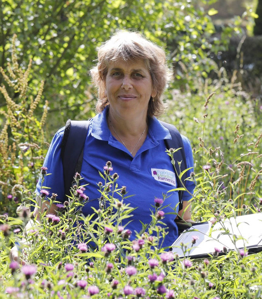 Photo of Dr Irina Tatarenko in a meadow with a clipboard