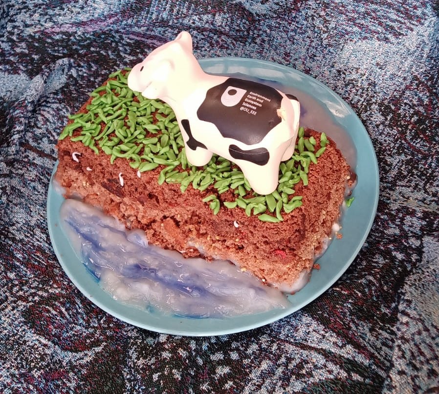 Image of a cake shaped as a cow on grass