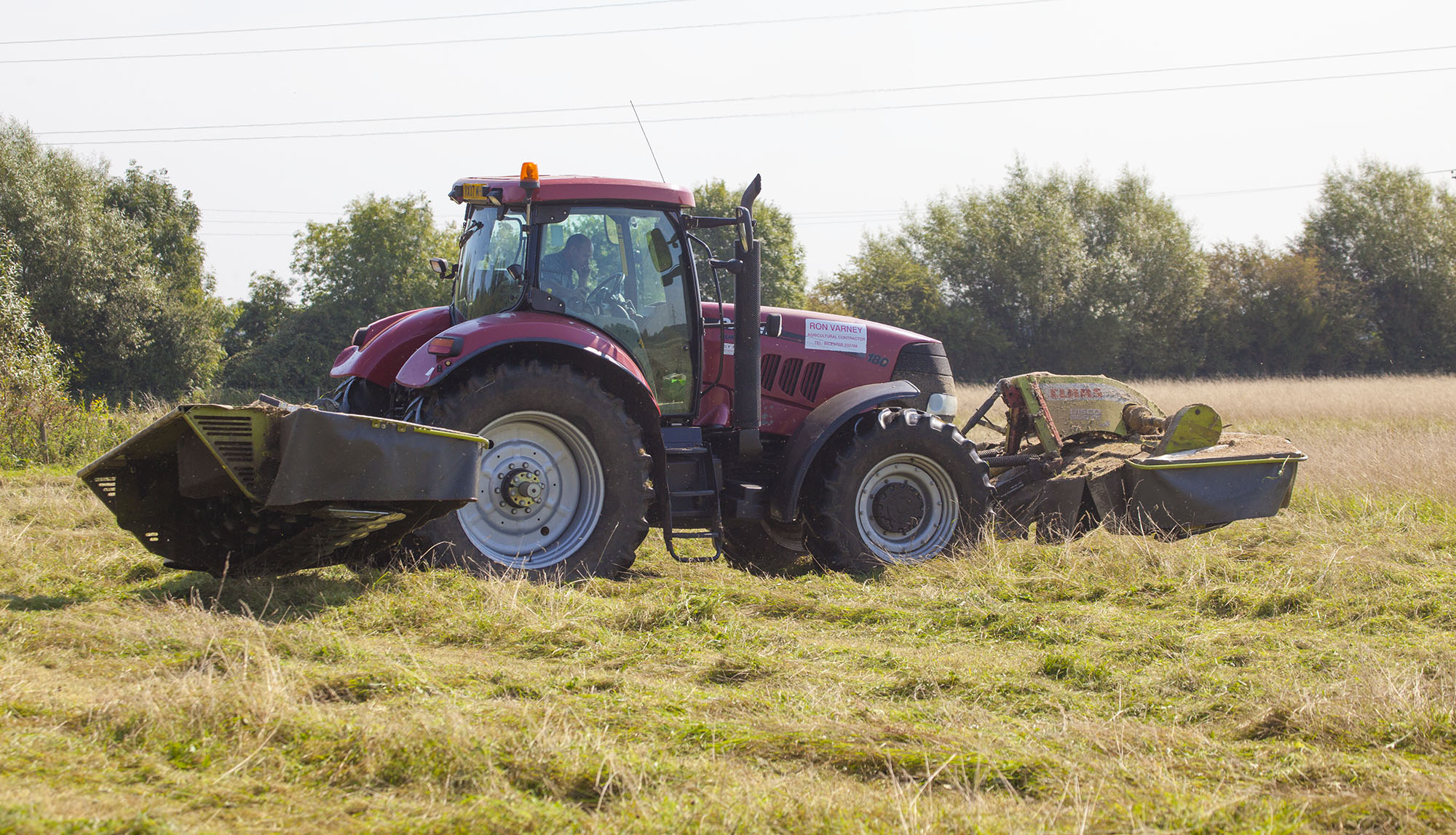 Tractor cutting grass in a field to make hay