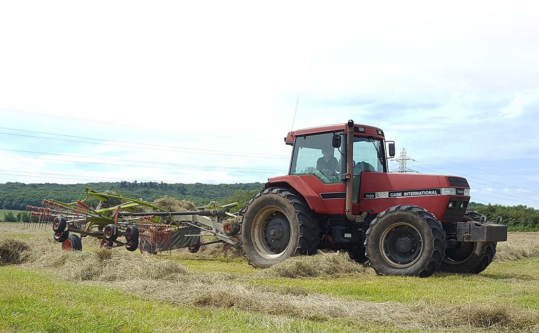 Red tractor cutting hay
