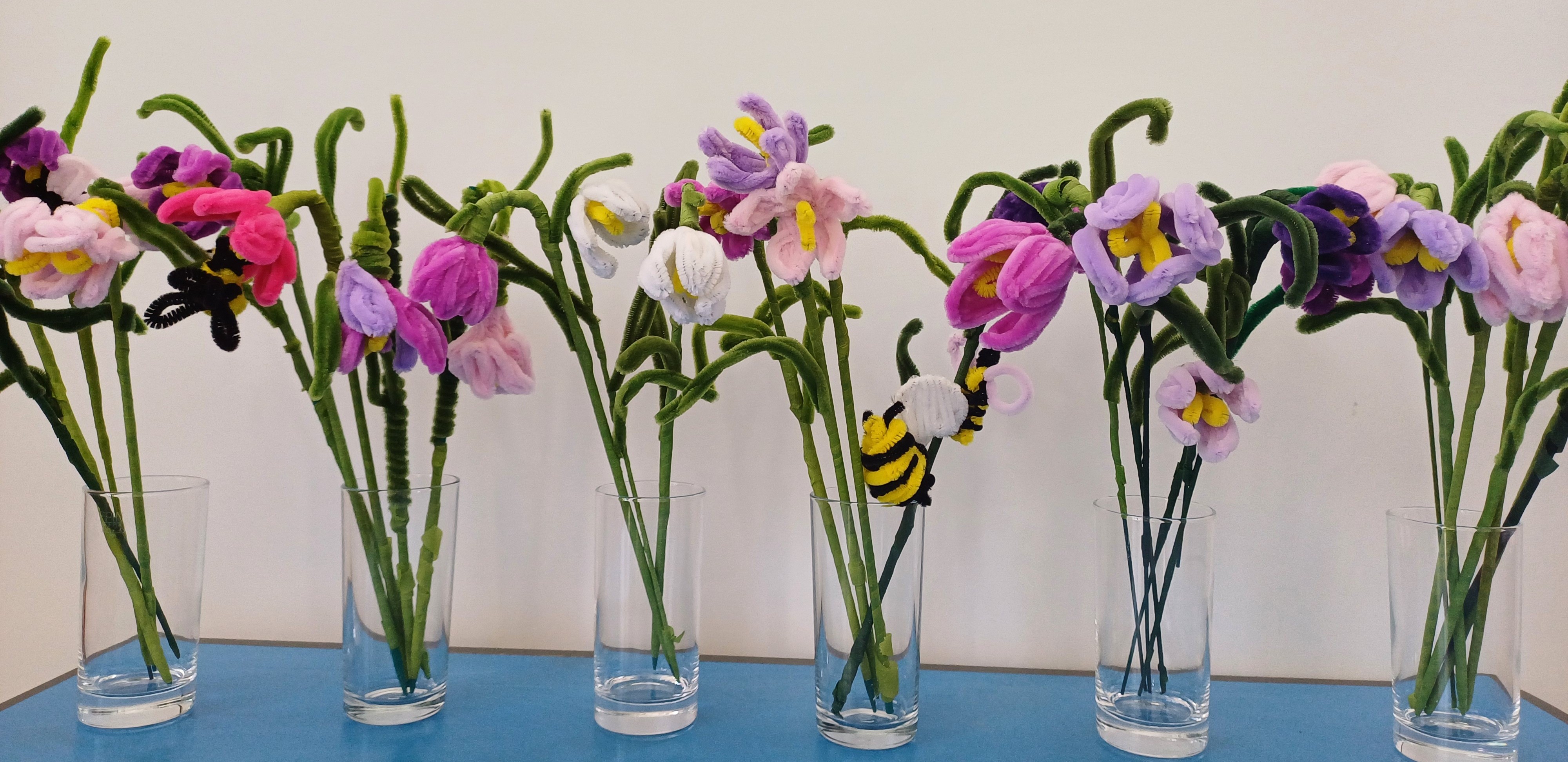 A row of pipecleaner flowers in vases